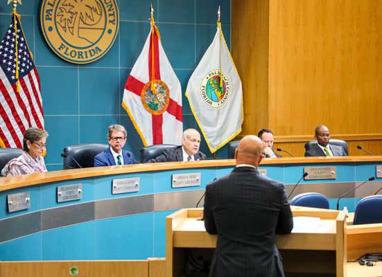 Clerk Abruzzo stands in front of the County Commissioners